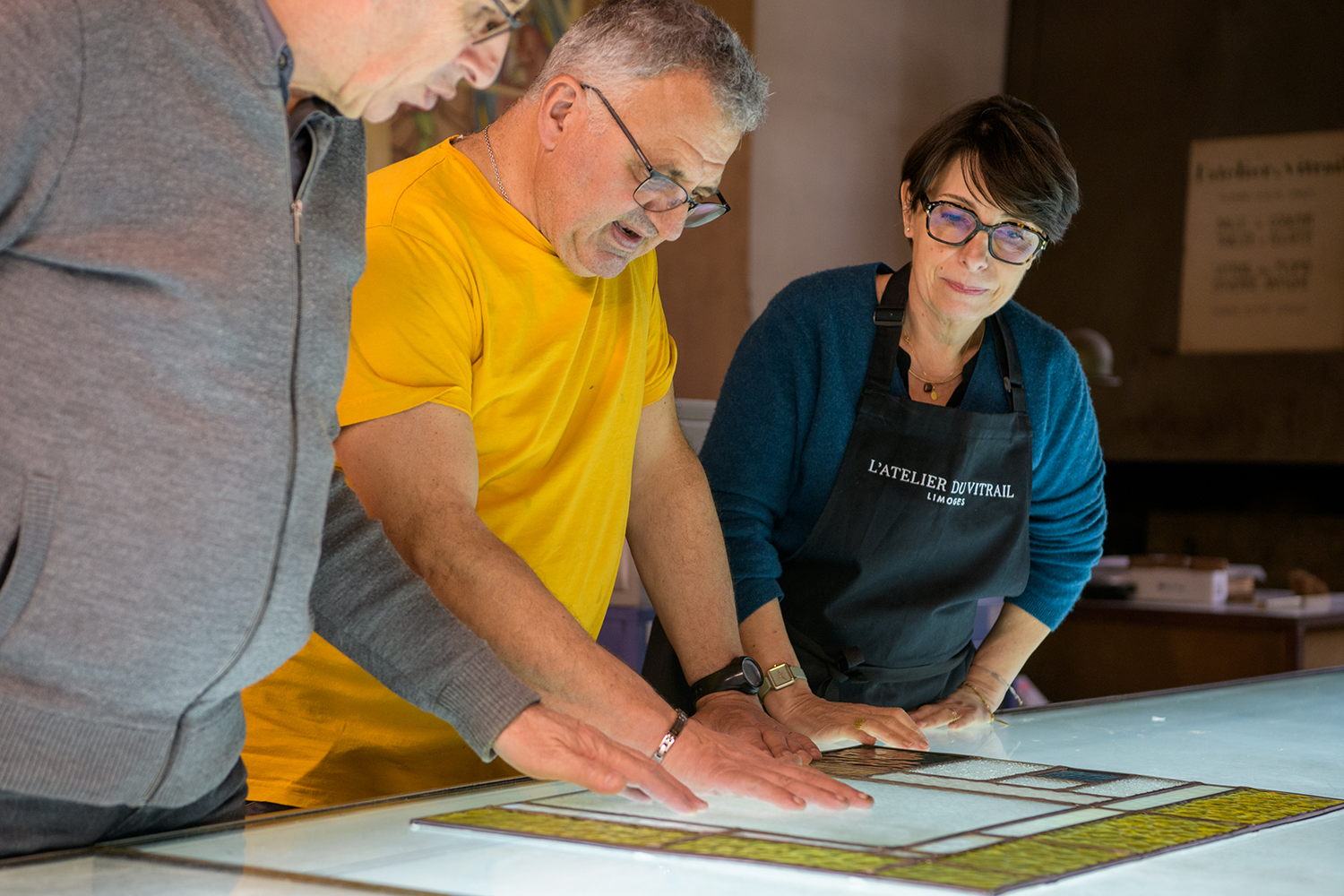 De gauche à droite, Didier Bayle, gérant, Éric Commergnat, chef de chantier et Sandrine Coulaud, directrice, tous les trois à l’Atelier du vitrail, se concertent sur le sort qui sera réservé à l’un des vitraux qu’ils restaurent. 